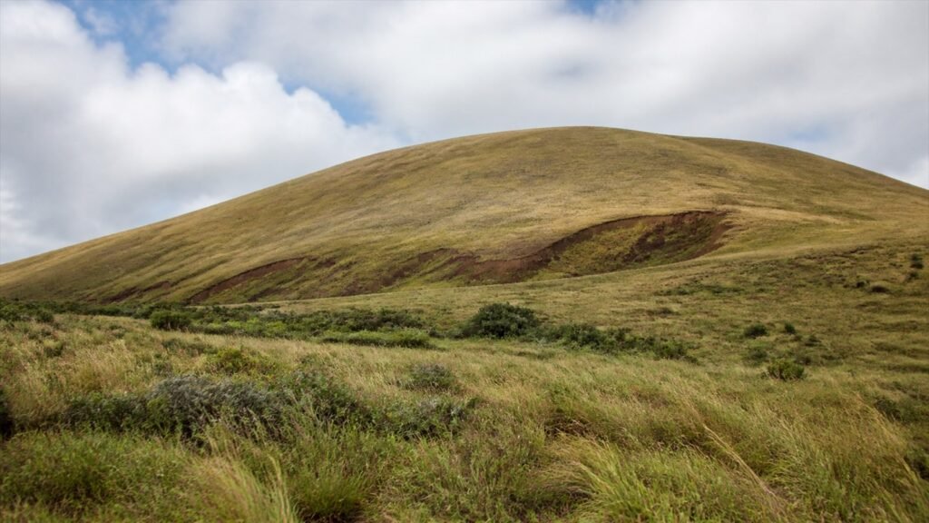 منحدر Rano Raraku البركاني بعشب منخفض وصخور تحت ضوء متقلب بلا زوار